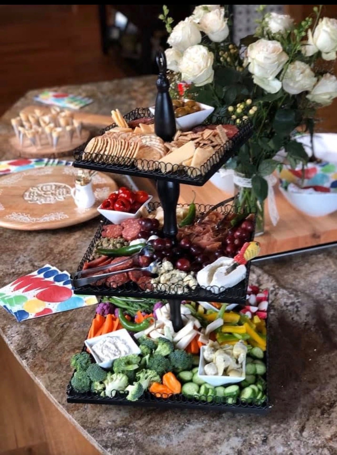 Three-tier charcuterie display with fresh vegetables and roses